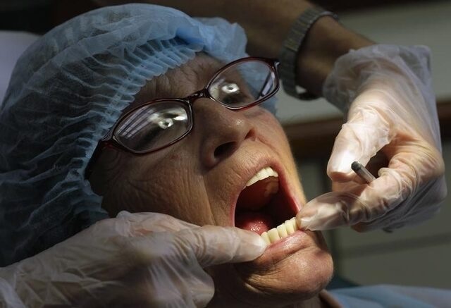 A dentist checks the teeth of a U.S. patient, at a dental clinic in San Jose, November 1, 2012. REUTERS/Juan Carlos Ulate