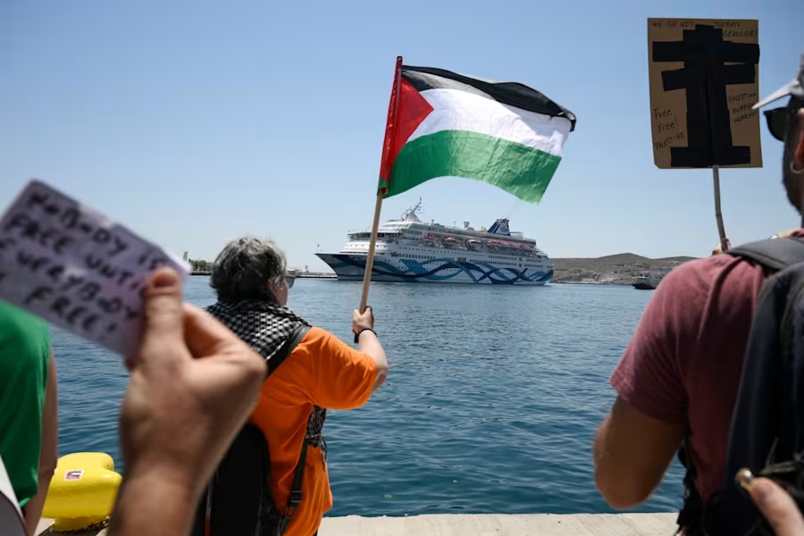 A protester waves a Palestinian flag as people demonstrates in front of a cruise ship carrying Israeli tourists and trying to approach the Aegean Sea island of Syros, Greece, Tuesday, July 22, 2025. (Nikos Panagiotopoulos/InTime News via AP)