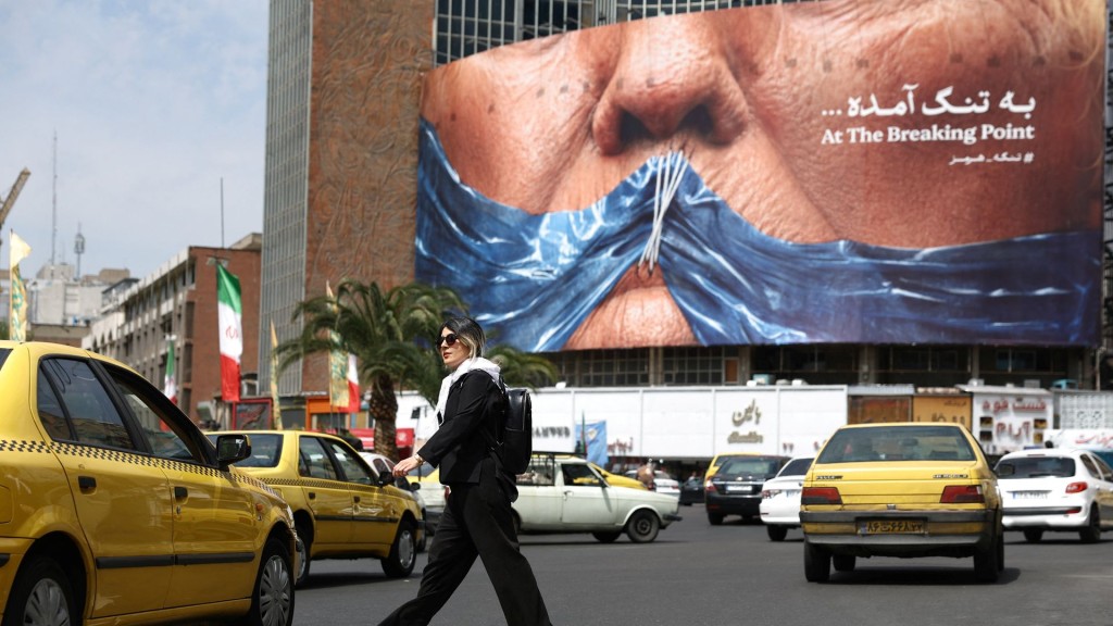 A woman walks past an anti-U.S. billboard depicting U.S. President Donald Trump and the Strait of Hormuz, in Tehran. Reuters