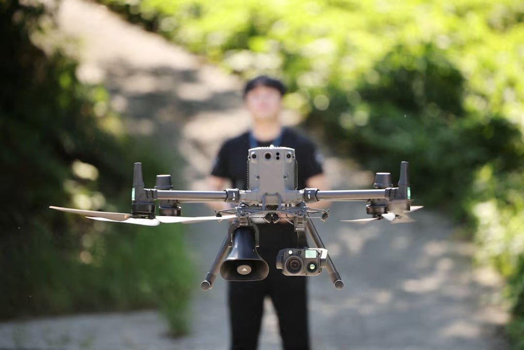 Hwang Han-jae, a public servant from the Safety and Administration Office of Gyeongsangbuk-do Provincial Government, flies a drone equipped with loudspeakers and thermal imaging camera over a chilli pepper field during a heat wave warning in Andong, South Korea, August 6, 2026. REUTERS/Kim Hong-Ji 