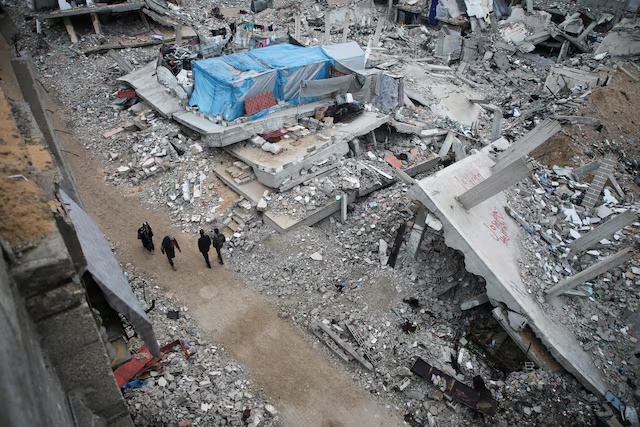Palestinians walk past the rubble of houses destroyed in previous Israeli strikes, ahead of a ceasefire set to take effect on Sunday, in Khan Younis in the southern Gaza Strip January 16, 2025. REUTERS/Hatem Khaled Palestinians walk past the rubble of houses destroyed in previous Israeli strikes, ahead of a ceasefire set to take effect on Sunday, in Khan Younis in the southern Gaza Strip January 16, 2025. REUTERS/Hatem Khaled