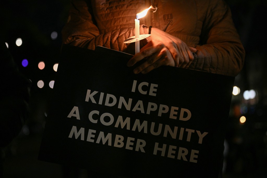 A person holds a candle during a "Vigil for Victims of ICE Violence" to honor those impacted by immigration enforcement actions in the Mount Pleasant neighborhood of Washington, DC, on October 16, 2025. (Photo by Brendan SMIALOWSKI / AFP)