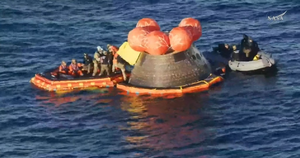 Photo by - / NASA / AFP  This video grab made from a NASA livestream shows Artemis II crewmembers (in orange suits) being extracted from their spacecraft after splashing down in the Pacific Ocean off the coast of San Diego, California, on April 10, 2026.