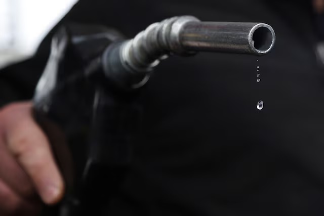 A gas station mechanic holds a nozzle connected to a gas pump as a gasoline drips out in Somerville, Massachusetts, U.S., March 7, 2022. REUTERS/Brian Snyder 