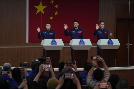 FILE - Journalists film Chinese astronauts for the upcoming Shenzhou 20 mission, from left, Wang Jie, captain Chen Dong and Chen Zhongrui wave at the Jiuquan Satellite Launch Center in northwest China, Wednesday, April 23, 2025. (AP Photo/Andy Wong, file)