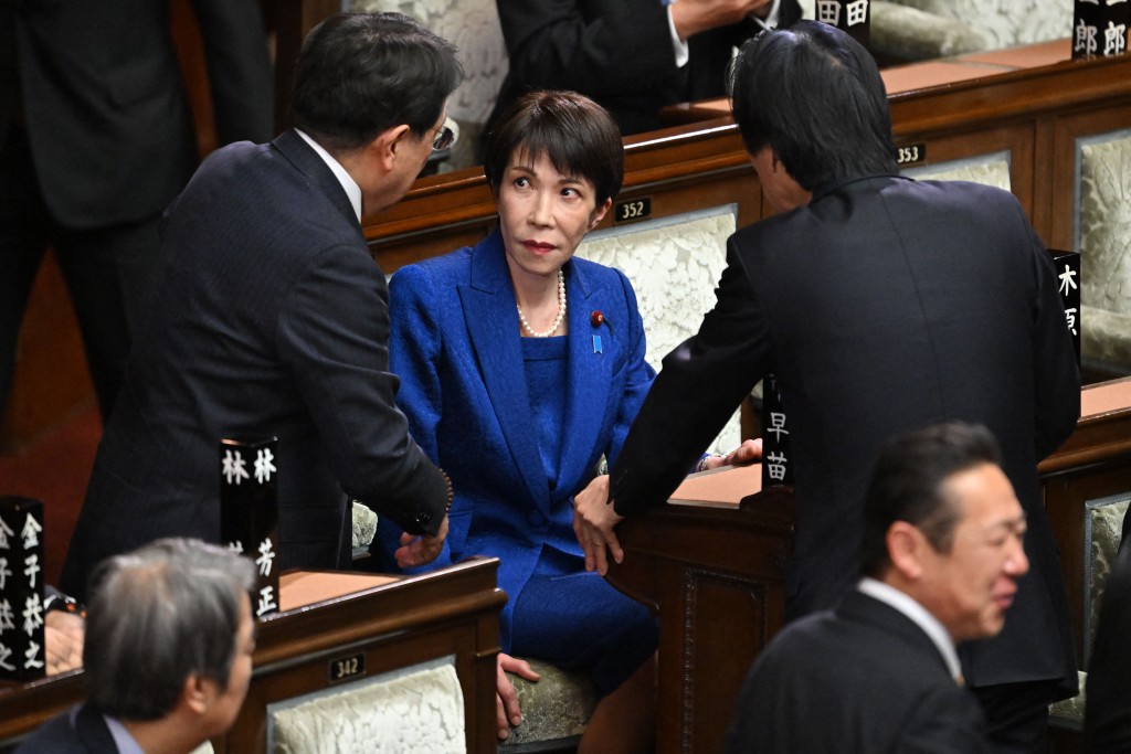 Photo by KAZUHIRO NOGI / AFP  Japan's Prime Minister Sanae Takaichi (C) chats with diet members before a plenary session of the House of Representatives at the Diet in Tokyo on January 23, 2026.