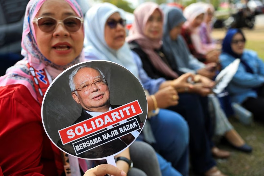 A supporter of former Malaysian Prime Minister Najib Razak holds a hand fan with a picture of Najib printed on it, outside the Malaysian Federal court, where his case is being heard at Putrajaya, Malaysia, August 13, 2025. REUTERS/Hasnoor Hussain