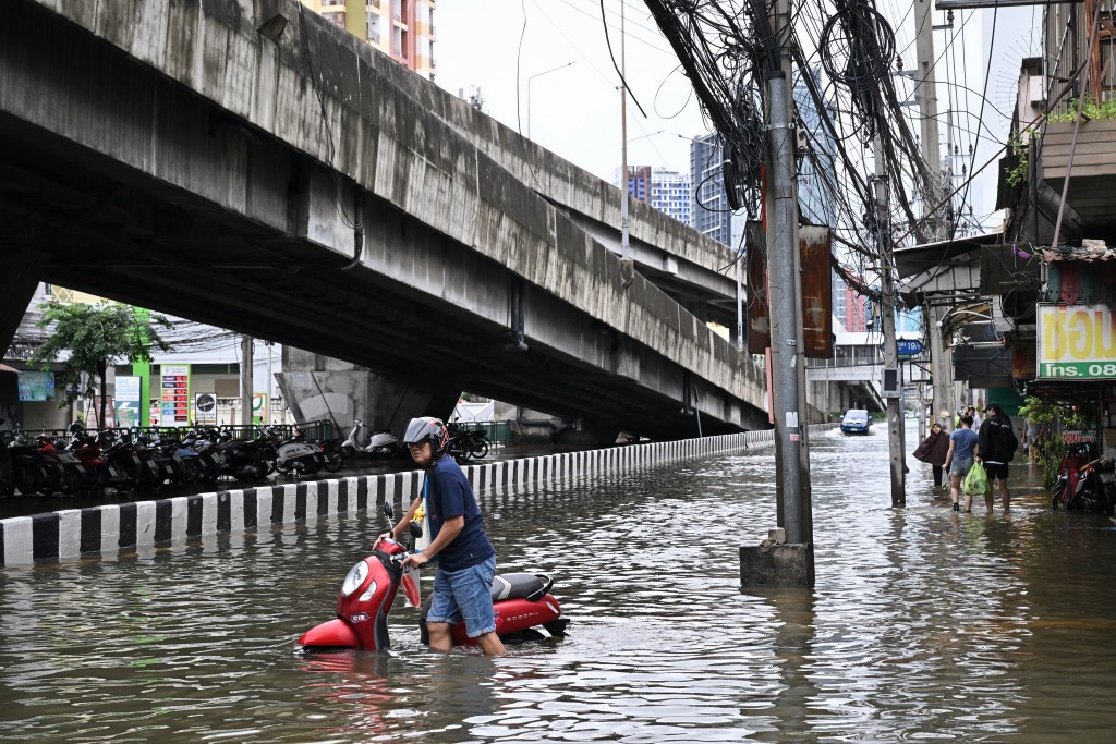 A man pushes a bike on a flooded road in Ramkhamhaeng district in Bangkok on September 27, 2026. (AFP)