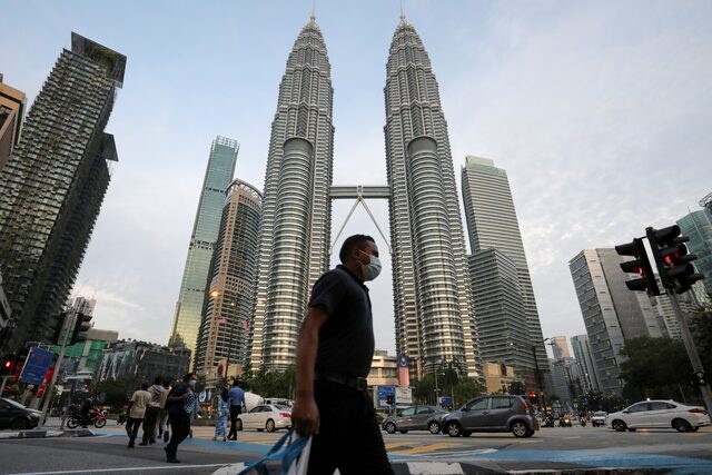 A man wearing a protective mask crosses a street in front of Petronas Twin Towers, amid the coronavirus disease (COVID-19) outbreak in Kuala Lumpur, Malaysia August 11, 2020. REUTERS/Lim Huey Teng 