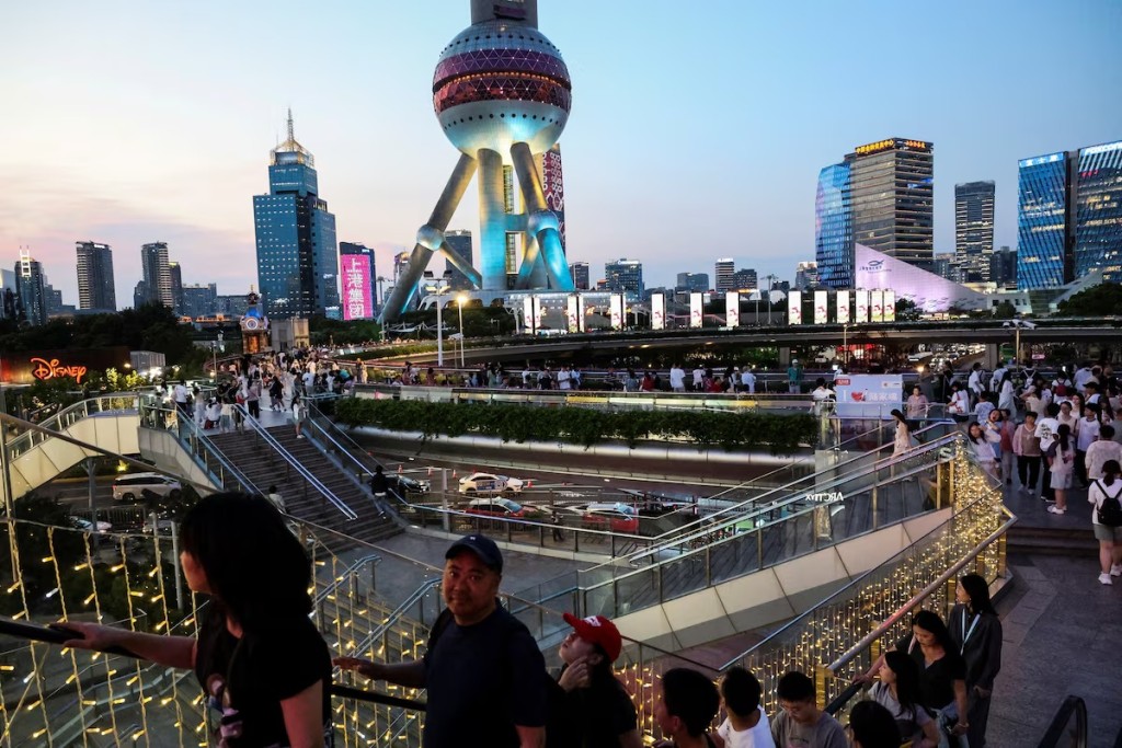 People walk on a pedestrian bridge at Lujiazui financial district in Shanghai, China, July 14, 2025. REUTERS