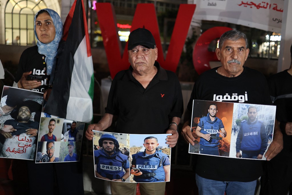 Protesters hold pictures denoucing the killing of an Al Jazeera news team in an overnight Israeli strike in Gaza City, during a vigil in Ramallah, in the occupied West Bank on August 11, 2025. Condemnations poured in from the United Nations and media rights groups on August 11, after an Israeli strike killed an Al Jazeera staff members in Gaza, as Palestinians mourned the journalists and Israel accused one of them of being a Hamas militant. (Photo by Zain JAAFAR / AFP)