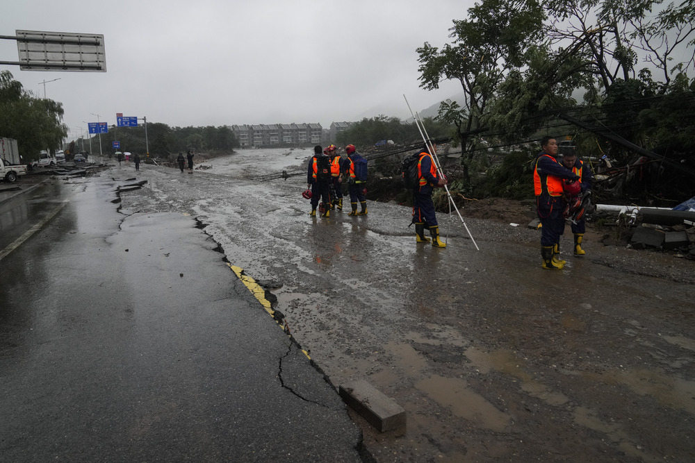 A rescue team works at a riverbank damaged by flood water. The swollen Yongding River churns up debris in brown torrents. AP, AFP