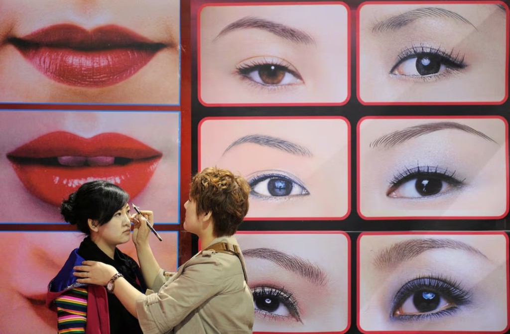 A beautician puts on make-up for a model in front of an advertisement at a beauty and hairdressing expo in Taiyuan in China's Shanxi province April 6, 2009. REUTERS/Stringer CHINA OUT. NO COMMERCIAL OR EDITORIAL SALES IN CHINA/File Photo