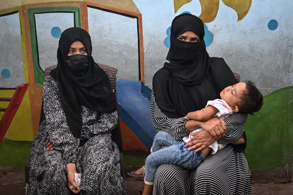 In this photograph taken on July 31, 2025, Amina (L), a household helper, sits beside her mother as she speaks during an interview with AFP in Karachi.  Photo by RIZWAN TABASSUM / AFP