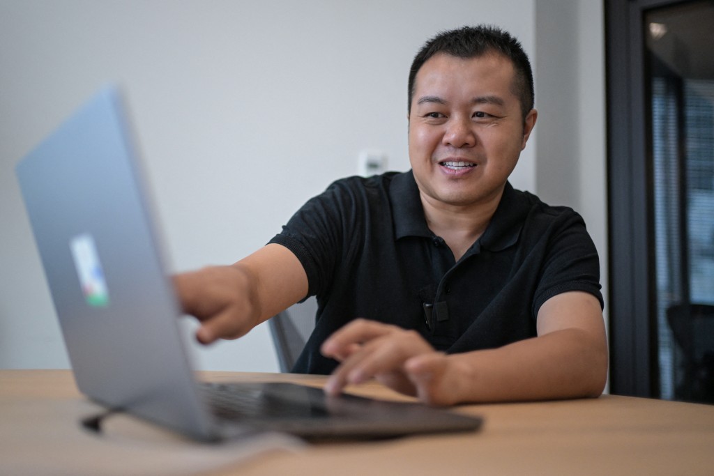 This photo taken on August 28, 2025 shows David Ha, the head of AI tech company Sakana AI, looking at his laptop during an interview at their offices in Tokyo. (Photo by Richard A. Brooks / AFP)