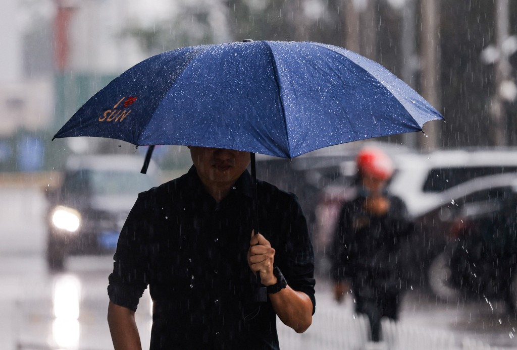 A man with an umbrella walks in the street during heavy rain in Beijing, China. (Reuters)