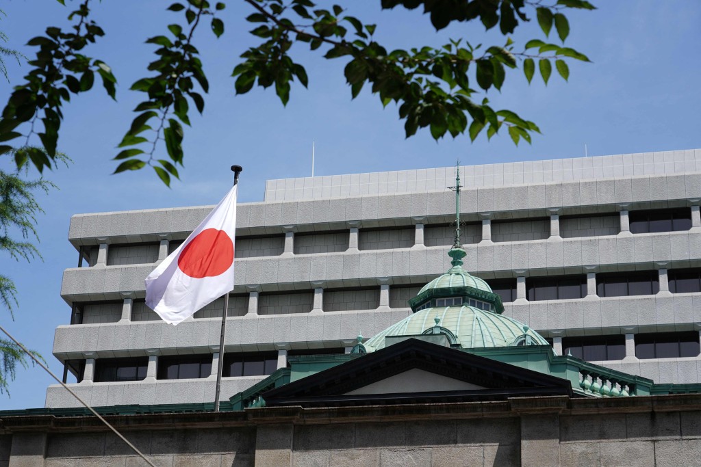 Japan's national flag flutters at the Bank of Japan headquarters building in Tokyo on June 16, 2026. The Bank of Japan is widely expected to hike interest rates to a 31-year high on June 16 as it battles inflation caused by the Middle East War, even after Washington and Tehran agreed a peace deal. (Photo by Kazuhiro NOGI / AFP)