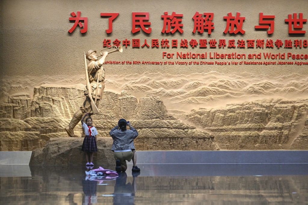 A child poses for photos in front of a sculpture as she visits an exhibition commemorating the 80th anniversary of the victory over Japan and the end of World War II at the Museum of the War of Chinese People's Resistance Against Japanese Aggression in Beijing on August 27, 2025. China will hold a military parade in Beijing on September 3 to mark the 80th anniversary of victory over Japan and the end of World War II. (Photo by WANG Zhao / AFP)