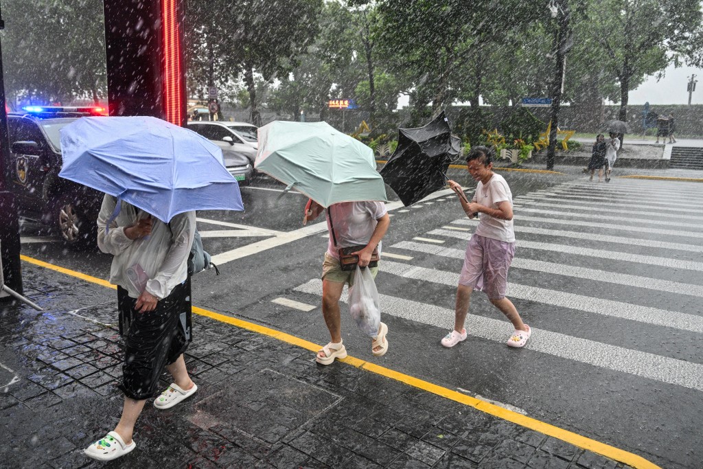 People use umbrellas to shelter from the rain as they walk on The Bund a day after Typhoon Dolphin made landfall in Shanghai on August 10. (AFP)