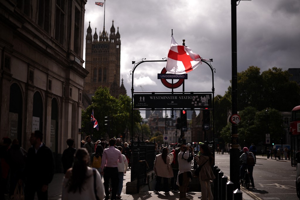 A St Georges Cross flag hangs from an Underground station sign in Westminster, central London on September 15, 2025, following protests on the weekend. (Photo by HENRY NICHOLLS / AFP)