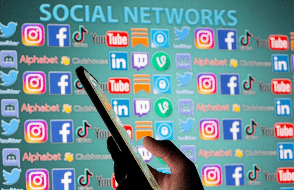 Woman with smartphone is seen in front of displayed social media logos in this illustration taken, May 25, 2021. REUTERS/Dado Ruvic/Illustration/File Photo