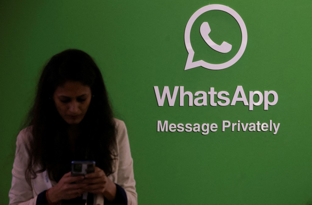  A woman uses her phone next to a logo of the WhatsApp application during Global Fintech Fest in Mumbai, India September 20, 2022. REUTERS