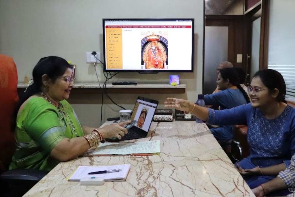 Laksmi Chandana, shows a picture of her brother who lives in Australia, to Vanaja Rao, owner of a matchmaking agency, to look for suitable prospect, in Hyderabad, India, October 1, 2025. REUTERS/Almaas Masood