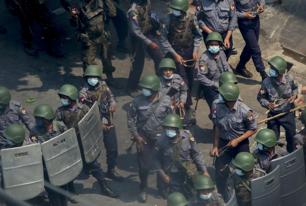 Policemen and soldiers armed with guns and slingshots advance towards anti-coup protesters in Mandalay, Myanmar, Wednesday, March 3, 2021.