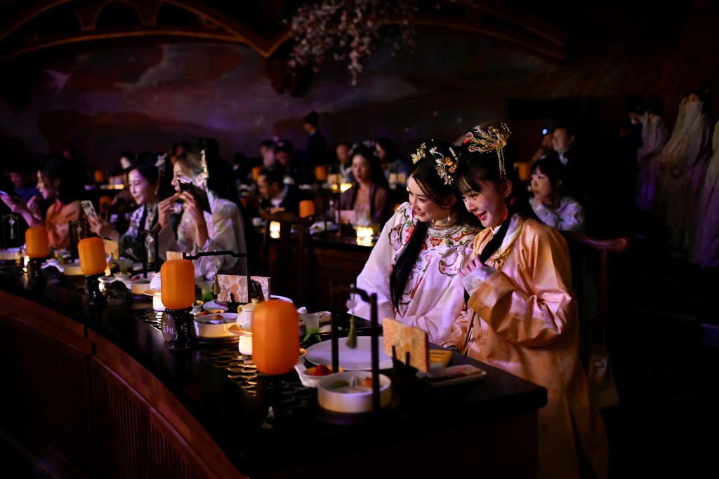 Photo by WANG ZHAO / AFP  This picture taken on November 2, 2025 shows people in traditional Chinese clothes having their meals at a theatrical restaurant in Beijing.
