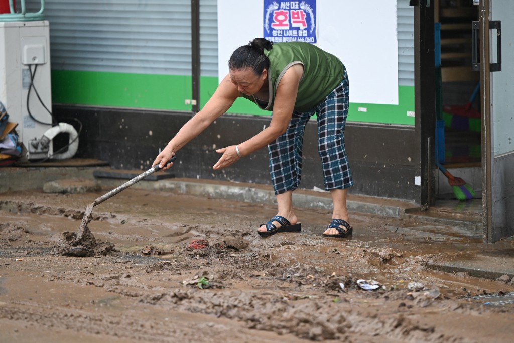 A woman removes mud in front of her store after flooding caused by record-breaking rains in Seosan on July 17, 2025. (AFP)