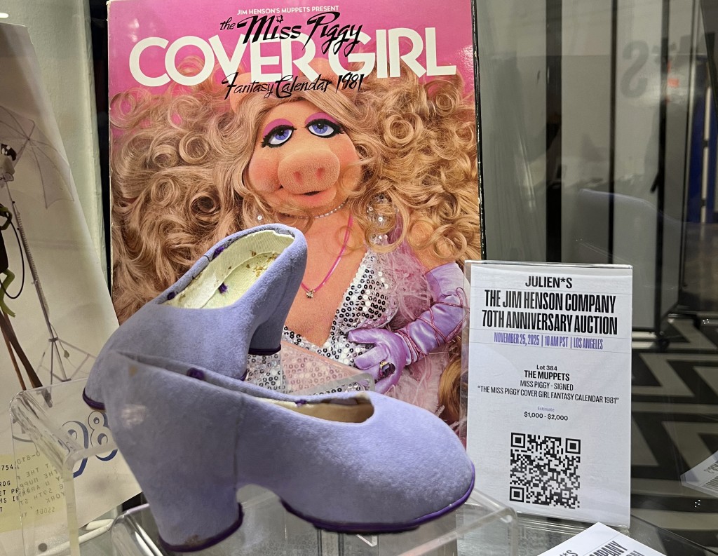 Photo by PAULA RAMON / AFP  The Miss Piggy signed Cover Girl fantasy calendar 1981 is on display with a pair of her production-worn shoes for "Couldn't We Ride" bicycle scene of "The Great Muppet Caper" are displayed during a preview of the Jim Henson Company 70 years anniversary auction at Julien's Auctions warehouse in Gardena, California on November 19, 2025.