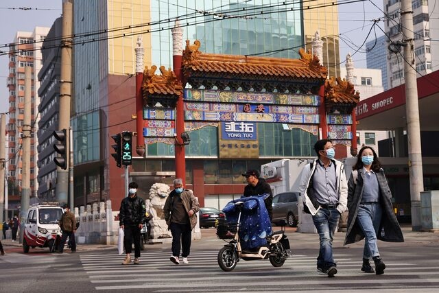 People wearing face masks cross a street in Beijing, Reuters