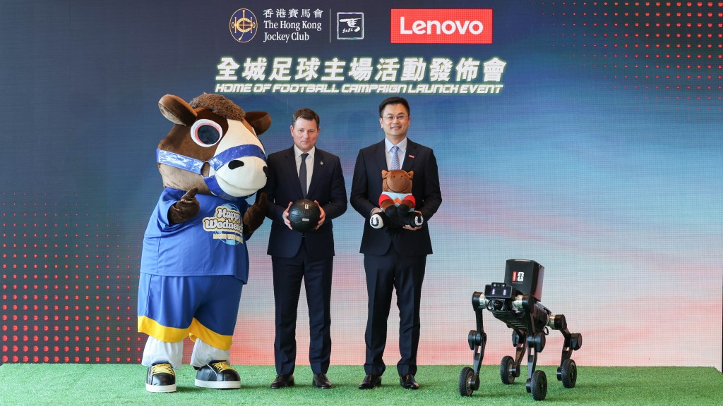 To mark the new partnership between The Hong Kong Jockey Club and Lenovo, Casper Stylsvig, the Club’s Executive Director, Sports Business (left), together with “Racing with Football” mascot present Lenovo with Ka Ying Rising horse plush. Ken Wong, Executive Vice President of Lenovo and President of Lenovo’s Solutions & Services Group (right) presents the Club with a special-edition Lenovo football, joined by Lenovo’s AI-powered robot dog.