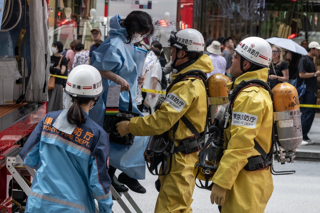 Emergency personnel help a woman that was inside the Ginza 6 Shopping Center out of an emergency vehicle in Tokyo on May 25, 2026, after an individual allegedly sprayed a substance in the area. (AFP)