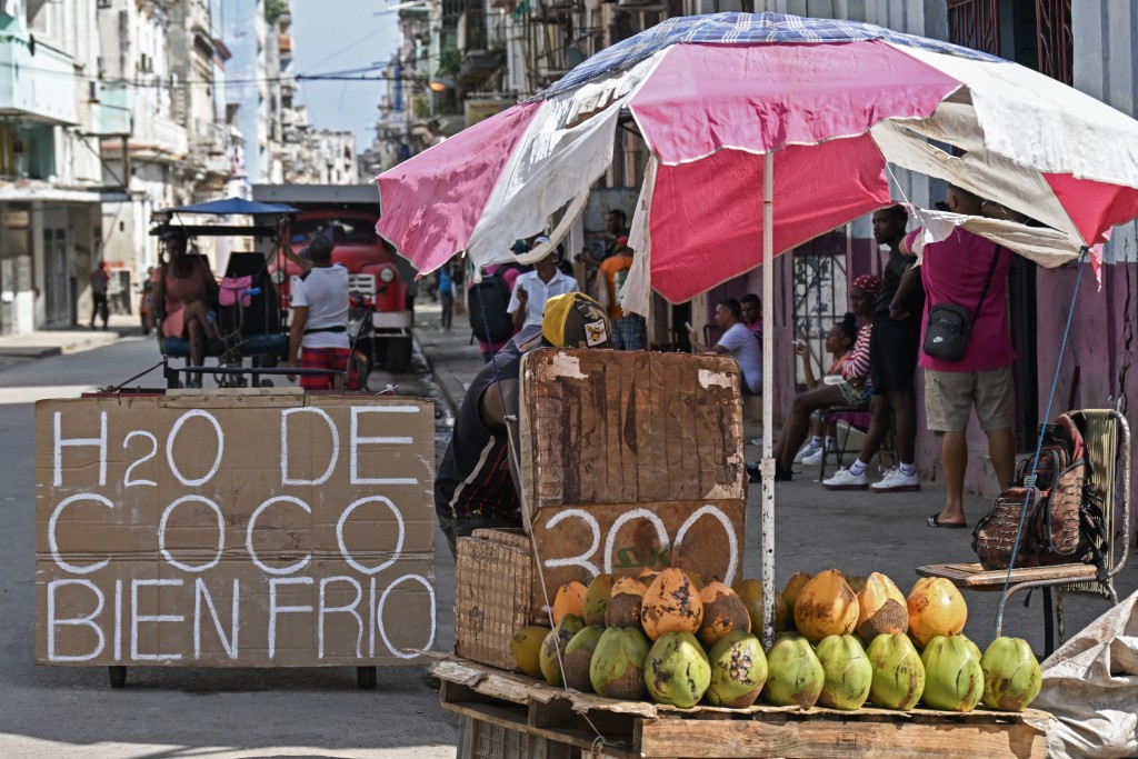Photo by YAMIL LAGE / AFP  A coconut water stall is seen on a street in Havana with a sign reading "Ice-cold coconut water", on March 16, 2026.