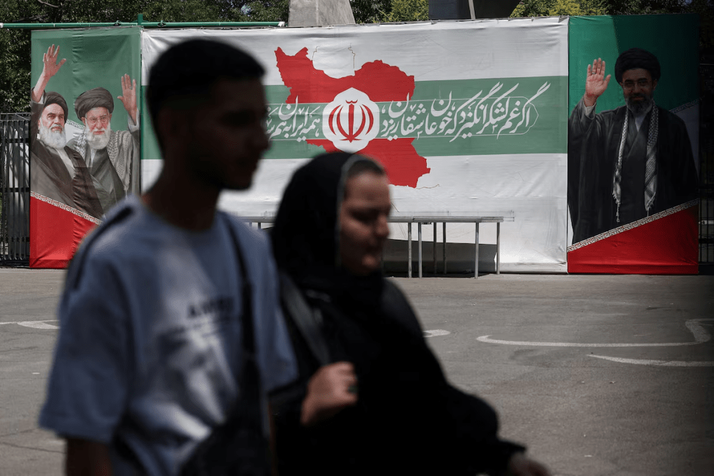 People walk past a banner with pictures of the late leader of the Islamic Revolution, Ayatollah Ruhollah Khomeini, the late Iran's Supreme Leader Ayatollah Ali Khamenei, and Iran's Supreme Leader Mojtaba Khamenei, on a street in Tehran, Iran, June 9, 2026. Majid Asgaripour/WANA (West Asia News Agency) via REUTERS