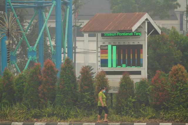 A woman wearing a protective face mask walks past near an air quality display while haze from wildfires covers the area in Pontianak, West Kalimantan province, Indonesia, September 3, 2026. REUTERS/Victor Fidelis Sentosa