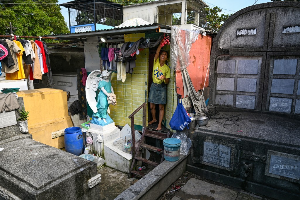 Photo by JAM STA ROSA / AFP  This photo taken on October 21, 2025 shows resident Laileah Cuetara fixing her laundry outside her makeshift house at Manila North Cemetery in Manila.