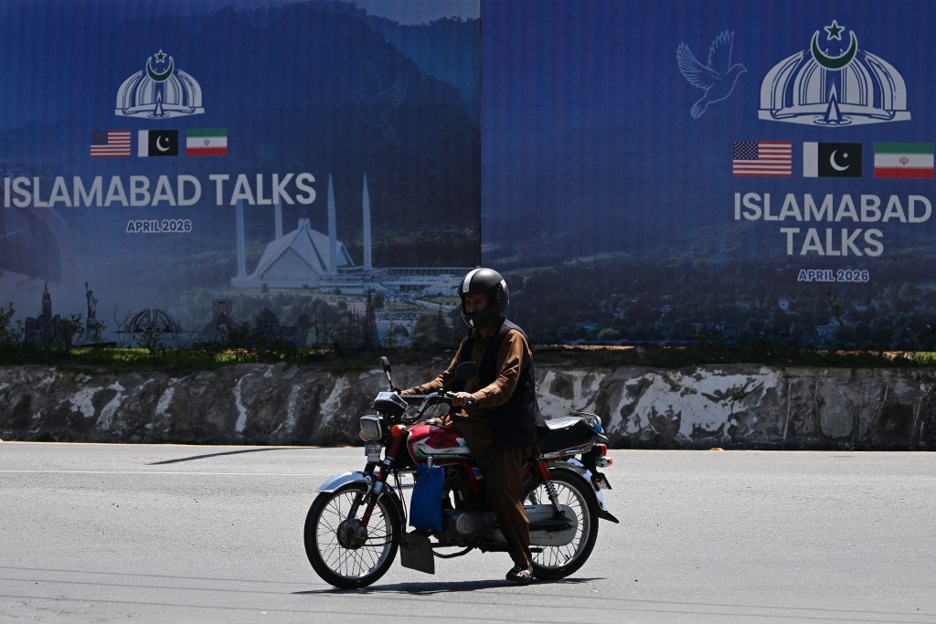 A commuter rides past a billboard for the US-Iran peace talks in Islamabad on April 13, 2026 a day after the Iran and the United States failed to reach an agreement to end the war in the Middle East. (AFP)