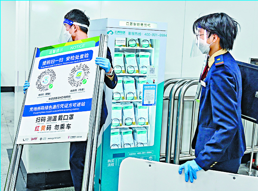 Workers remove posters for Covid health code use at the entrance of a subway in Guangzhou as the mainland begins relaxing curbs. AFP