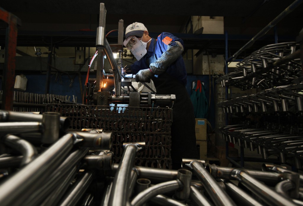 In this March 4, 2011 photo, a worker from the Dahon, the world's largest maker of folding bicycles, covering his face by paper card for protection, welds bicycle frames in Shenzhen, a city of southern China. AP Photo