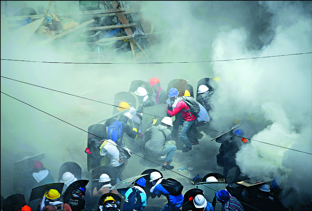 Protesters reel from tear gas fired by police in Yangon as they greet Aung San Suu Kyi's court appearance with more rallies. REUTERS Protesters reel from tear gas fired by police in Yangon as they greet Aung San Suu Kyi's court appearance with more rallies. REUTERS