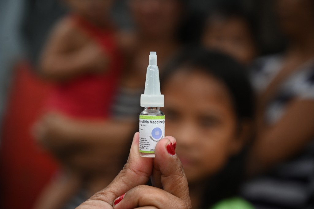 Photo by TED ALJIBE / AFP  A health worker displays a vial of polio vaccine during a government-run vaccination drive in Manila on October 14, 2019.