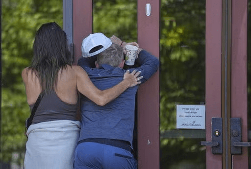 Kristen Neville, left, and Michael Burt cry and embrace each other at the doors of the Annunciation Catholic Church after Wednesday's school shooting, Thursday, Aug. 28, 2025, in Minneapolis. (AP Photo/Abbie Parr)