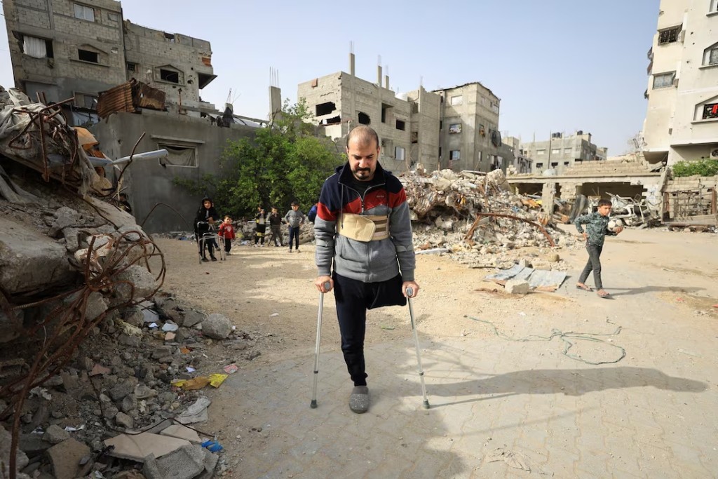 Palestinian amputee Hazem Foura, who lost one leg, walks using crutches in a street in Gaza City, April 3, 2026. REUTERS/Dawoud Abu Alkas 