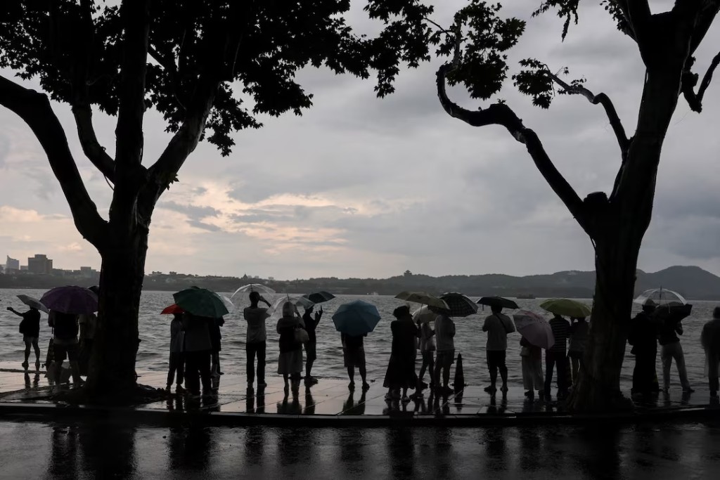 People use umbrellas in the rain by West Lake after a rainstorm warning was issued for the area in Hangzhou, Zhejiang province, China, July 21, 2026. REUTERS/Go Nakamura