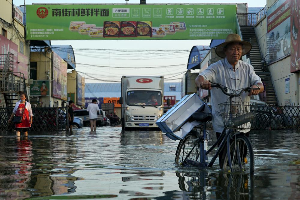A man carries goods on his bicycle as he walks out of the the Yubei Agricultural and Aquatic Products World in Xinxiang in central China's Henan Province, Monday, July 26, 2021.