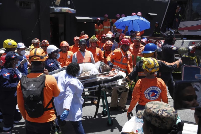 Rescue workers carry a person pulled from the wreckage - Ricardo Hernandez/AP