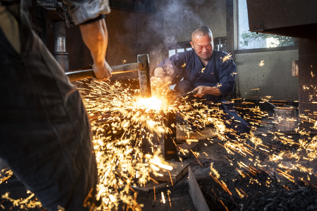 Photo by YUICHI YAMAZAKI / AFP  This picture taken on January 9, 2026 shows sparks flying as swordsmith Akihira Kawasaki (R) steadies steel over an anvil while his apprentice Toru Watanabe hammers the metal to forge katana blades at Kawasaki's workshop in Misato, Saitama prefecture.