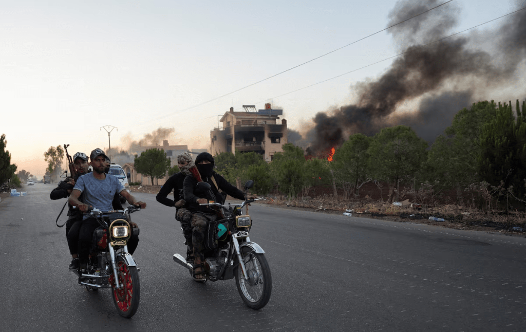 Bedouin fighters ride on motorbikes along a street, as Sweida province has been engulfed by nearly a week of violence triggered by clashes between Bedouin fighters and factions from the Druze, at Sweida governorate, Syria, July 18, 2025. REUTERS/Karam al-Masri